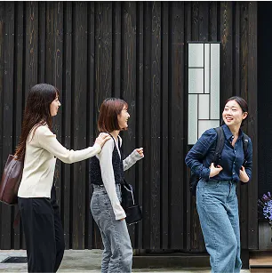 ホテルの前で笑顔で並ぶ3人の若い女性。